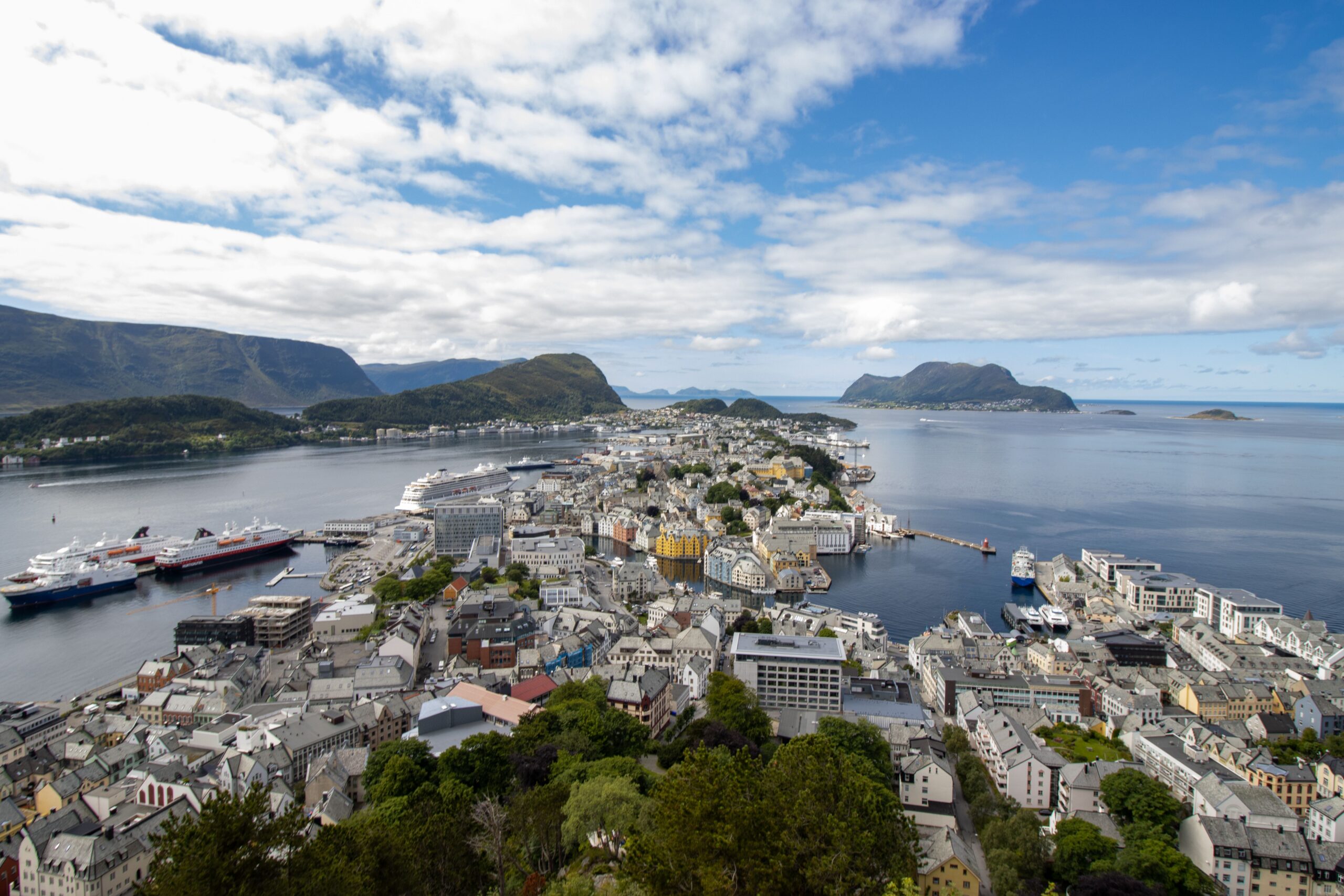 Stunning aerial view of Ålesund's harbor in Norway with scenic mountains in the background.